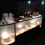 Illuminated refreshments bar features wine, cheese, assorted non-alcoholic beverages.